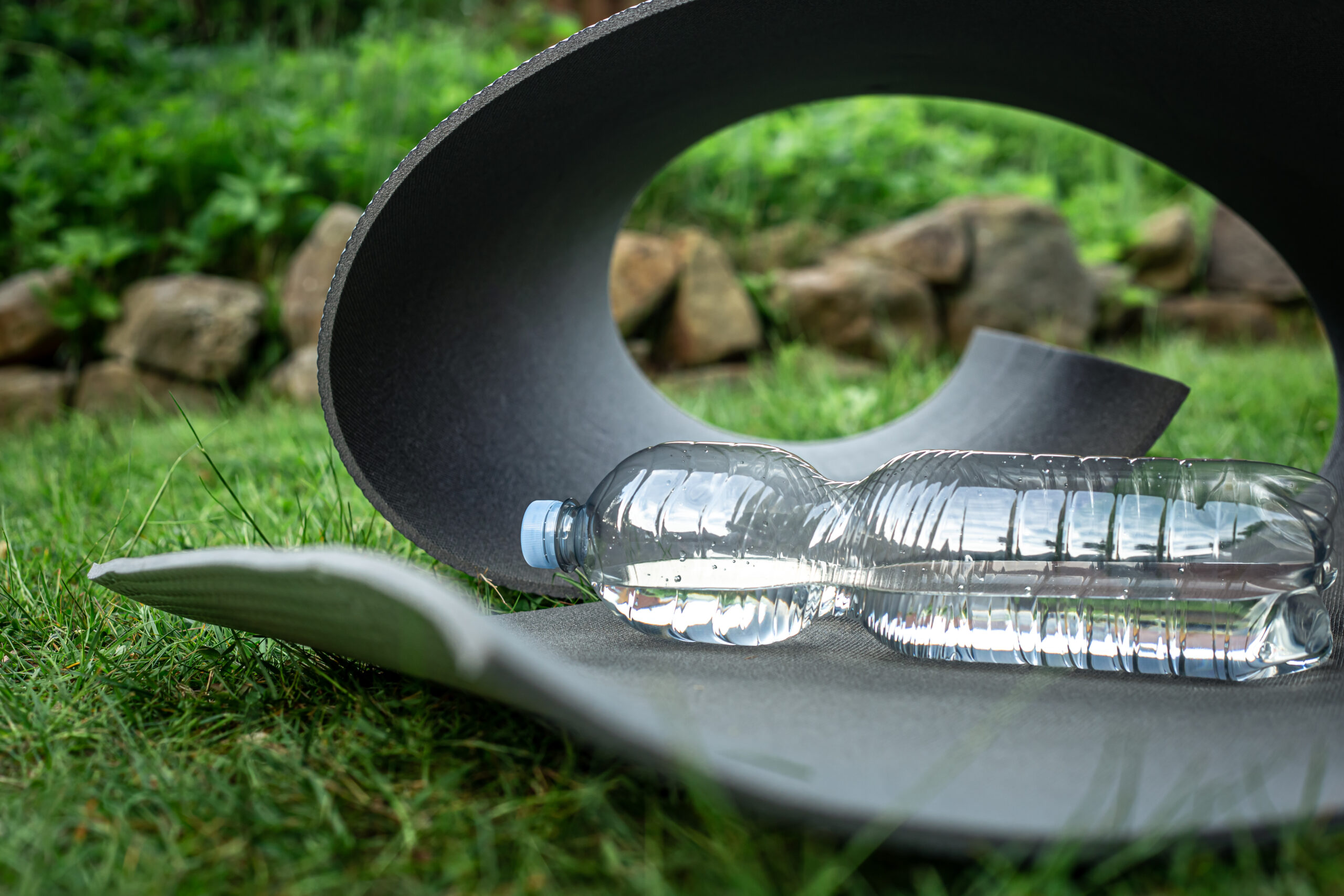 close up, bottle of water near yoga mat in nature.